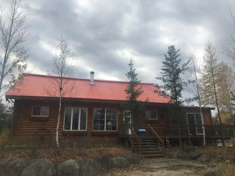 Vue extérieure de l'Auberge Escapade avec son toit rouge et sa terrasse en bois.