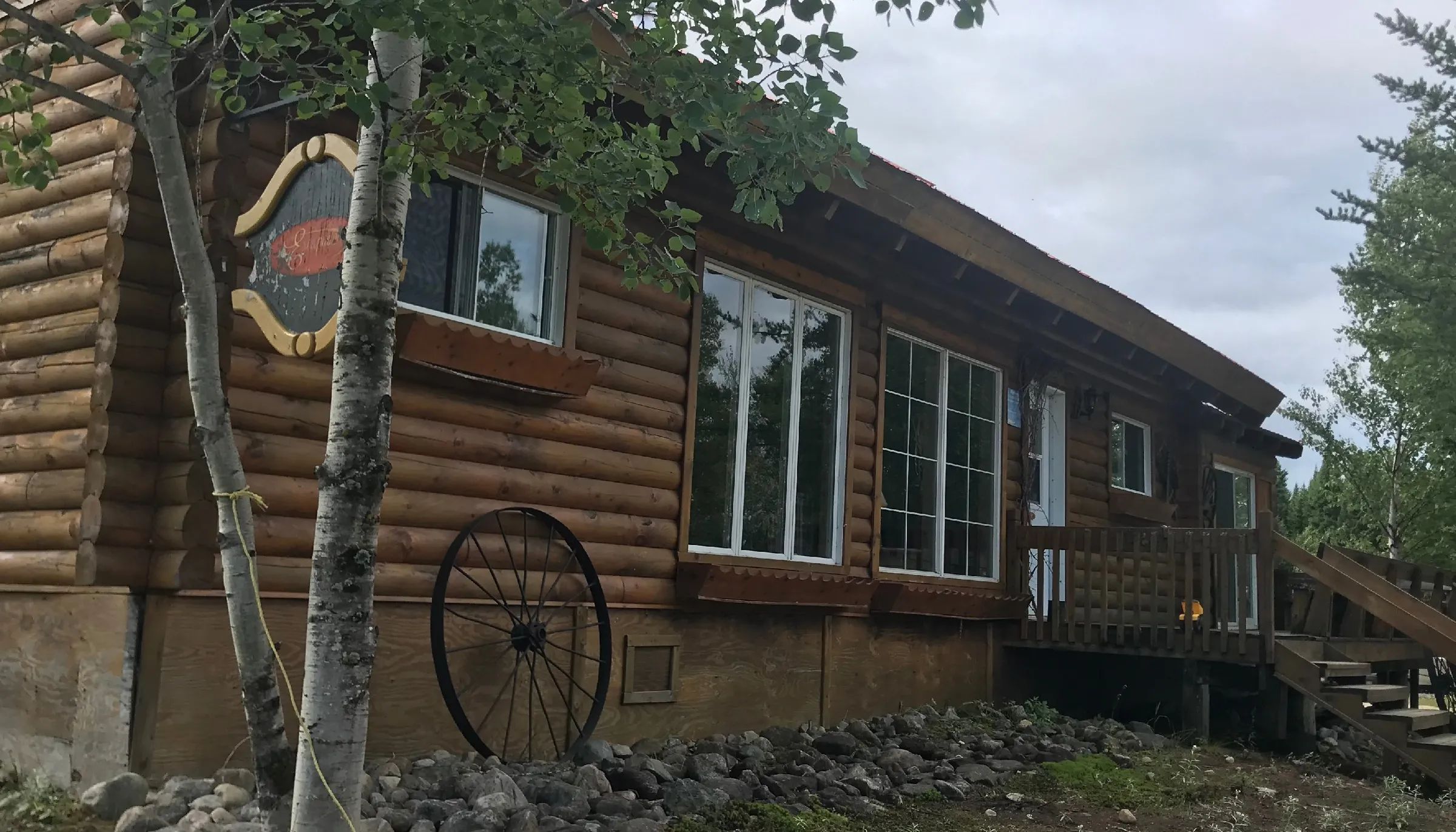 Vue latérale de l'Auberge Escapade construite en bois rond avec ses fenêtres et sa galerie extérieure.