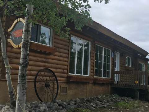 Vue latérale de l'Auberge Escapade construite en bois rond avec ses fenêtres et sa galerie extérieure.