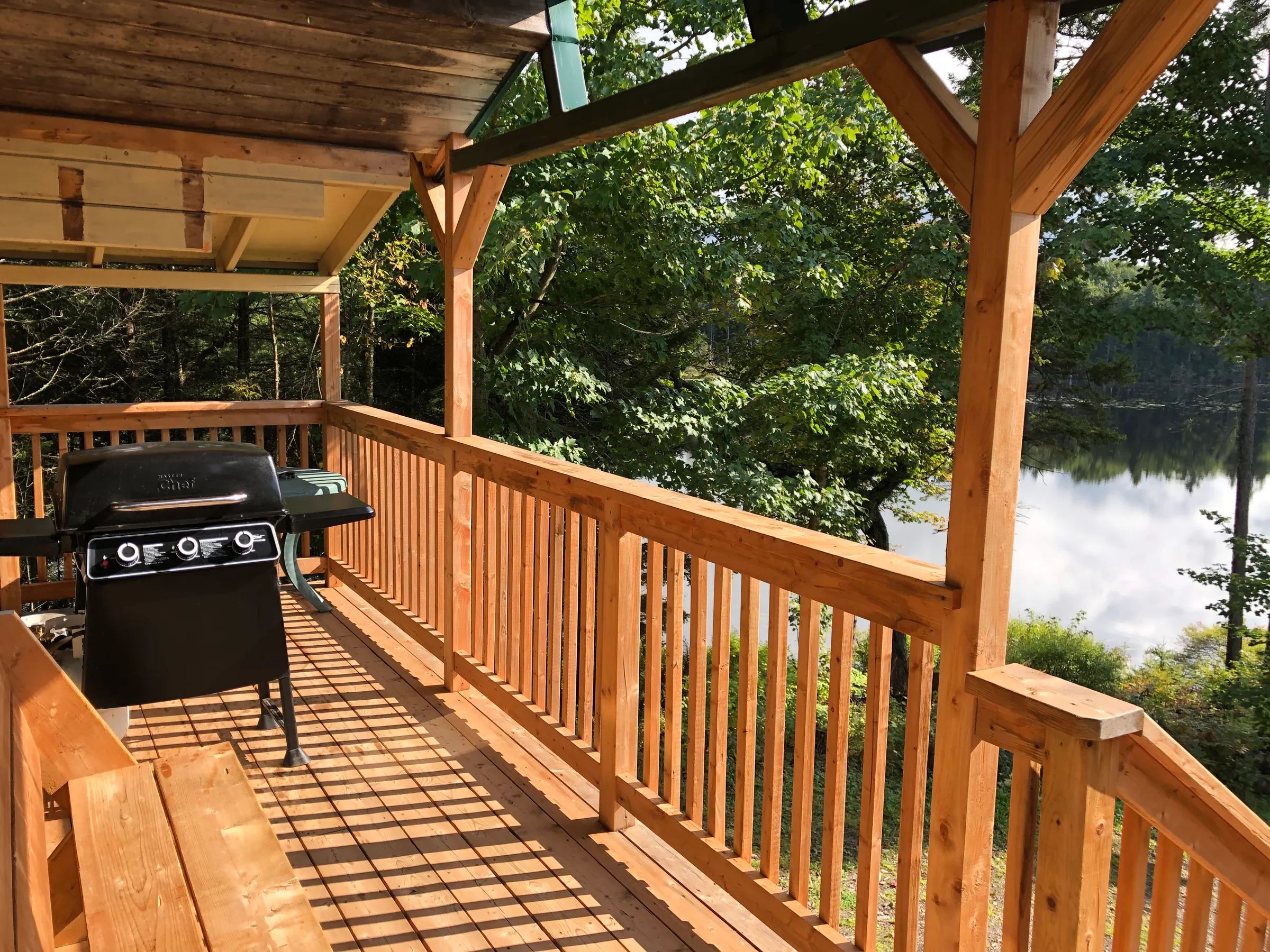 La galerie du chalet 4 offre un espace extérieur avec barbecue et vue sur la forêt et le lac.