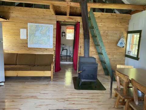 Cozy living space with wood stove, sofa, and access to a loft in the cabin.