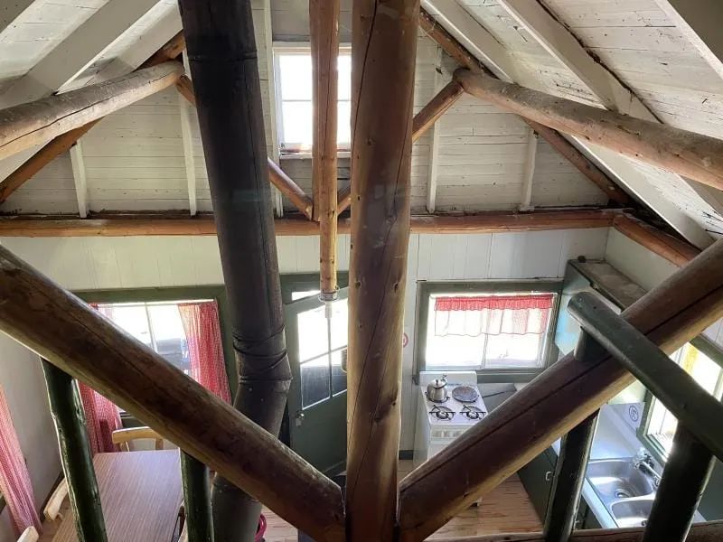 High-angle view of the cabin's ground floor, featuring its wooden structure and functional kitchen.