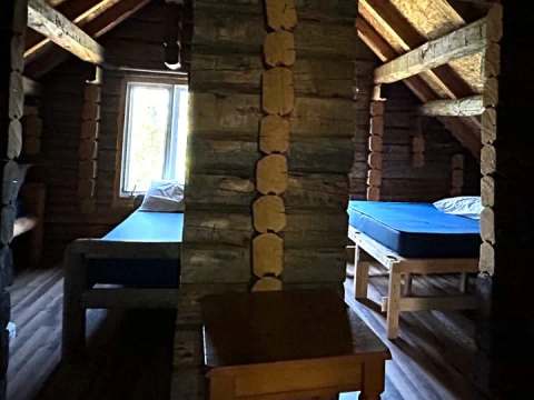 The rustic interior layout of the Hibou cabin featuring log beds.