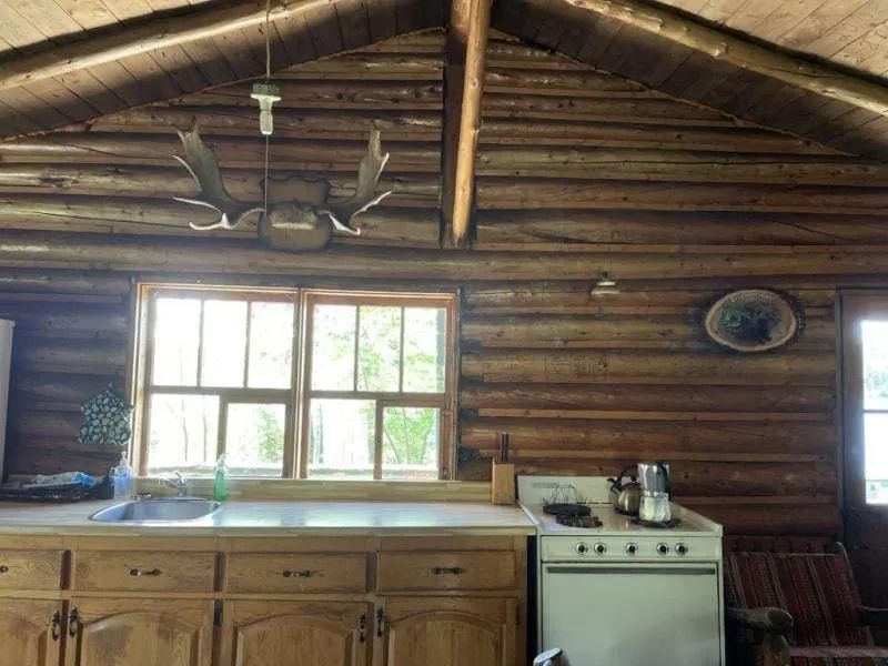 La cuisine en bois rond du chalet le Lynx dispose d'un évier et d'une cuisinière fonctionnelle.