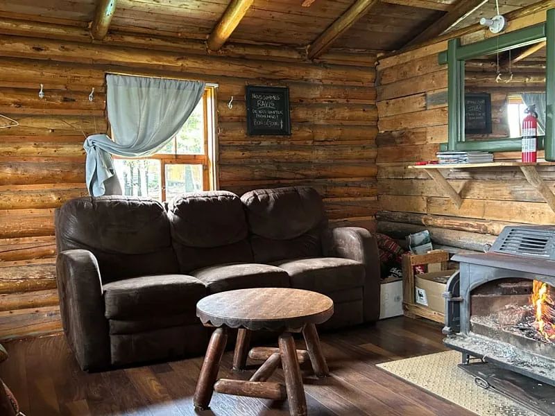 Le salon du chalet Le Lynx dispose d'un canapé confortable et d'un foyer au bois traditionnel.