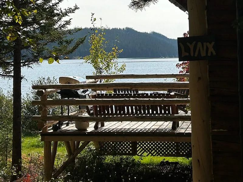 La terrasse en bois du chalet Le Lynx offre une vue relaxante sur le lac et la forêt.