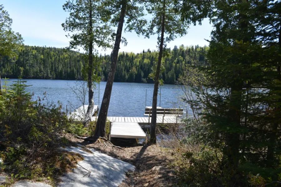 The dock at Chalet Alain provides direct access to the lake surrounded by the forest.