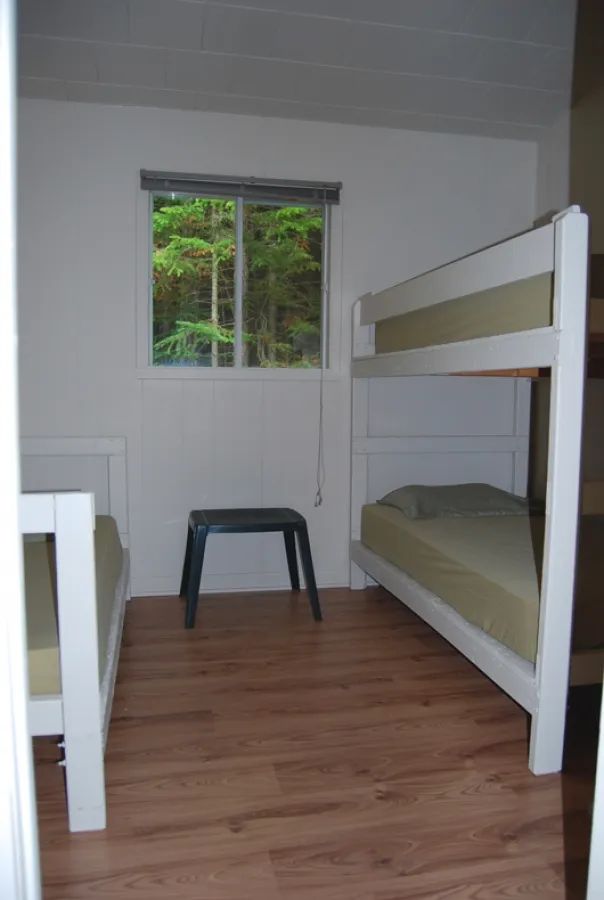 This bedroom in the Alain cabin features bunk beds and offers a view of the forest.