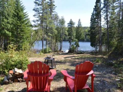 Deux chaises rouges font face au lac devant le Chalet Éliane.