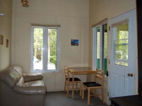 Le salon du chalet Éliane comprend un divan, une table à manger et un poêle à bois.