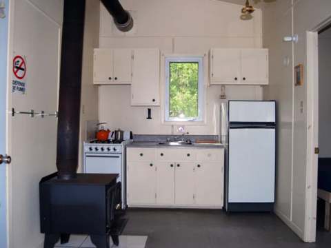 La cuisine fonctionnelle du chalet Éliane comprend une cuisinière, un réfrigérateur et un poêle à bois.