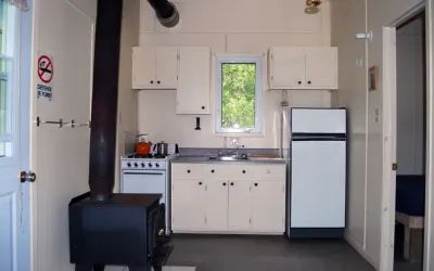 La cuisine fonctionnelle du chalet Éliane comprend une cuisinière, un réfrigérateur et un poêle à bois.