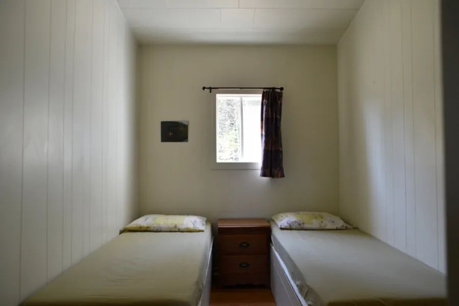 Cette chambre du chalet Pierre est équipée de deux lits simples avec une table de chevet.