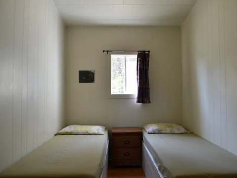 Cette chambre du chalet Pierre est équipée de deux lits simples avec une table de chevet.
