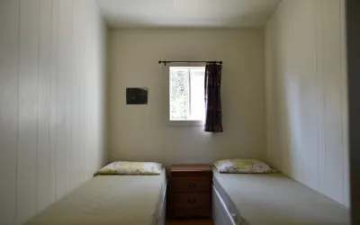 Cette chambre du chalet Pierre comprend deux lits simples et une table de chevet.