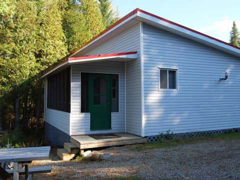 Vue extérieure du chalet Pierre avec sa galerie et sa table de pique-nique.