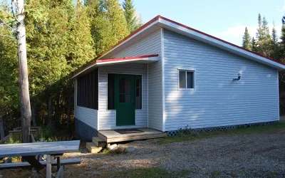 Vue latérale du Chalet Pierre avec sa porte d'entrée et sa table de pique-nique extérieure.
