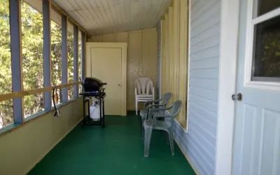 Une véranda grillagée avec barbecue et chaises au chalet Pierre.