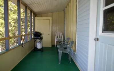 Une véranda grillagée avec barbecue et chaises au chalet Pierre.