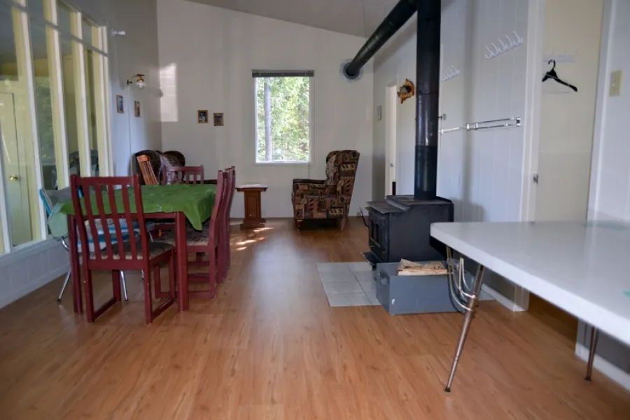 L'aire de séjour du chalet comprend une table à manger et un poêle à bois.
