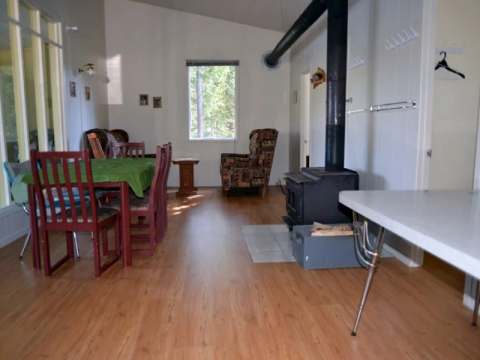 L'aire de séjour du chalet comprend une table à manger et un poêle à bois.