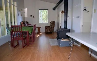 La salle à manger et le salon du Chalet Pierre incluent une table et un poêle à bois.