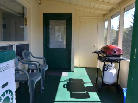 The screened porch of Chalet Samuel is equipped with chairs and a barbecue for your outdoor meals.