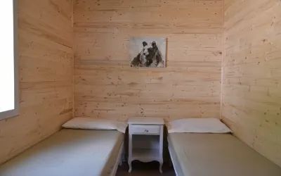 A bedroom with two single beds and a nightstand in the Samuel chalet.