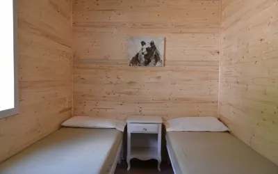 A bedroom with two single beds and a nightstand in the Samuel chalet.