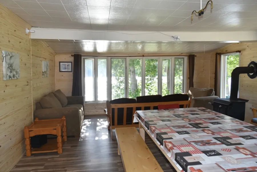 The open area of the chalet includes a living area with a lake view and a large dining table.