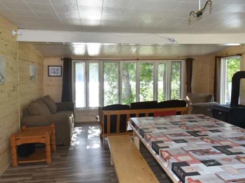 The open area of the chalet includes a living area with a lake view and a large dining table.