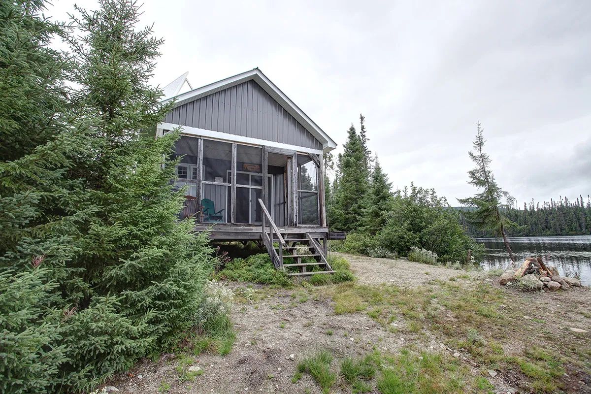 Ce chalet en bordure de lac dispose d'une véranda grillagée et d'un espace pour faire un feu.