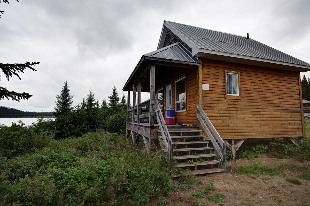 Side view of the La Chapelle cottage with its wooden entrance stairs and covered porch.