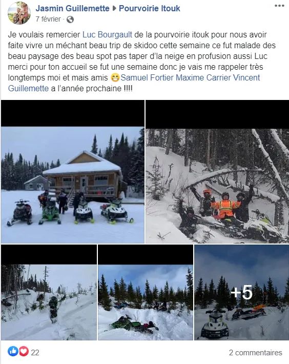 Un chalet en bois entouré de neige avec des motoneiges stationnées devant.