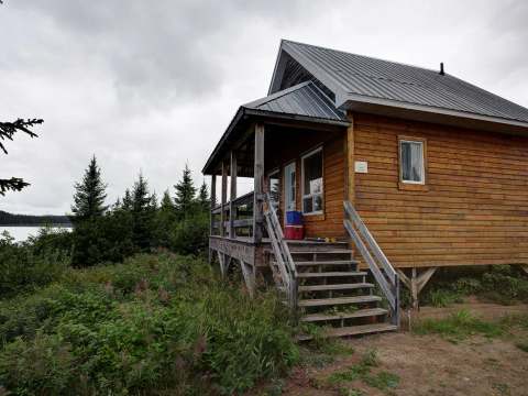 Side view of the La Chapelle cottage with its wooden entrance stairs and covered porch.