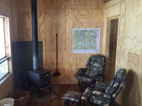 Interior view of the La Chapelle cabin with its wood stove and comfortable armchairs.