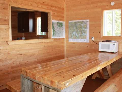 Cette cuisine et salle à manger en bois comprend une grande table et un comptoir de service.