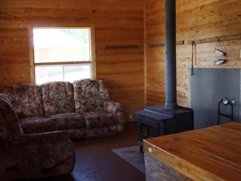 Le salon du chalet est aménagé avec un poêle à bois et des fauteuils confortables.