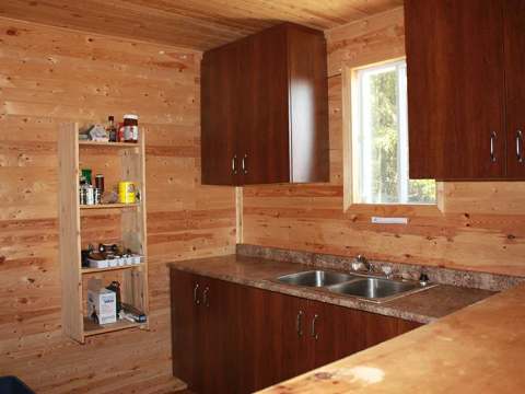 La cuisine fonctionnelle du chalet est dotée d'un évier double et d'espaces de rangement en bois.