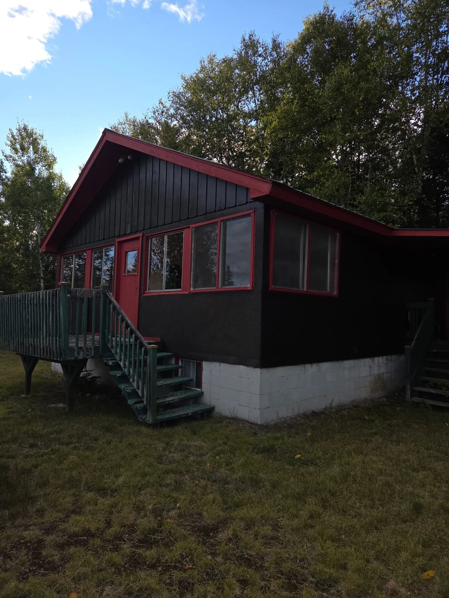 Vue extérieure du chalet 3 avec sa terrasse en bois et son revêtement sombre.