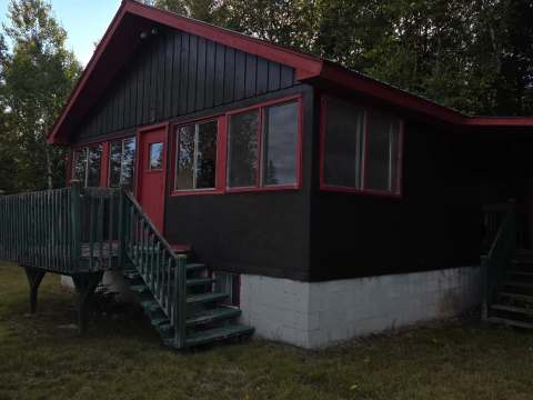 Vue extérieure du chalet 3 avec sa terrasse en bois et son revêtement sombre.