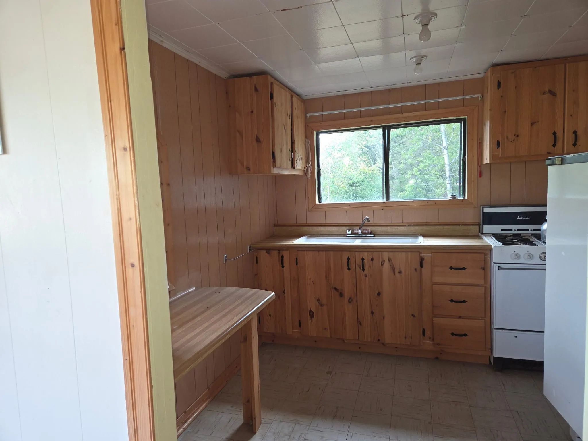 Cette cuisine de chalet fonctionnelle comprend des armoires en bois, une cuisinière et un comptoir.