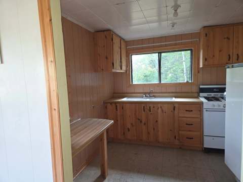 Cette cuisine de chalet fonctionnelle comprend des armoires en bois, une cuisinière et un comptoir.