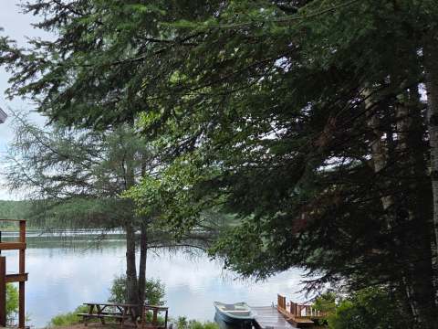 Vue sur le lac depuis le site du chalet 6 avec table de pique-nique et quai privé.