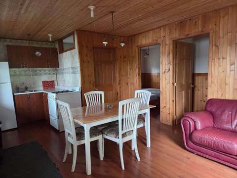 La cuisine et la salle à manger du chalet 6 sont aménagées avec une table, des chaises et un canapé.