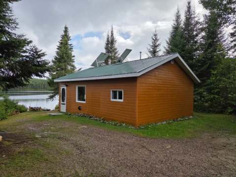 Le chalet 6 dispose d'un toit en métal vert et de panneaux solaires en bordure de lac.