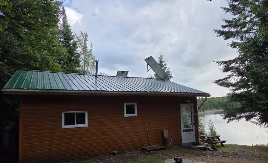 Le chalet 8 est situé en bordure de lac et possède un toit métallique avec des panneaux solaires.