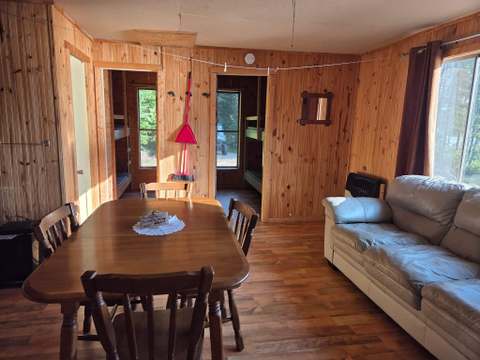 La salle à manger et le salon du chalet neuf proposent une aire ouverte en bois avec vue sur l'extérieur.