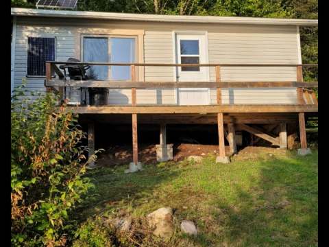 Vue extérieure du chalet 5 avec sa galerie en bois et ses panneaux solaires installés sur le toit.