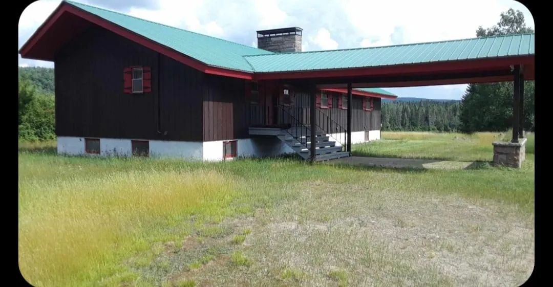 Vue extérieure du pavillon avec son toit vert et son abri pour voiture intégré.